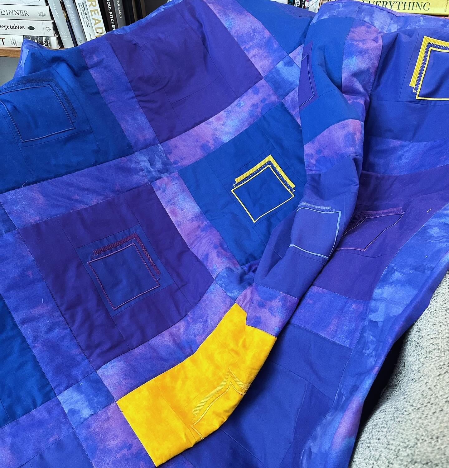 a purples and blues quilt with yellow accents