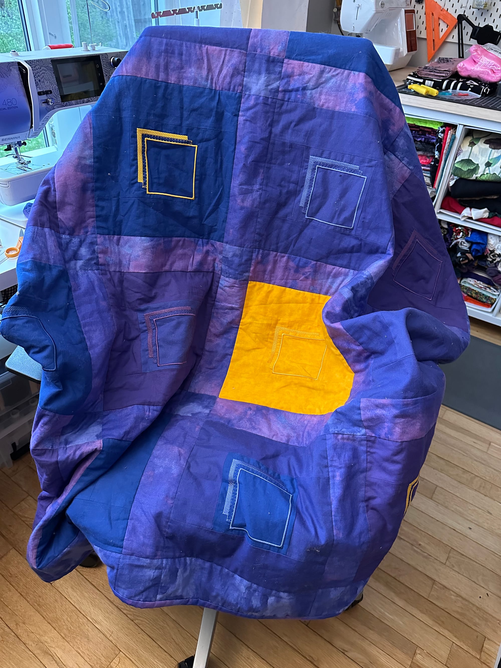 a purple and blue quilt with yellow accents