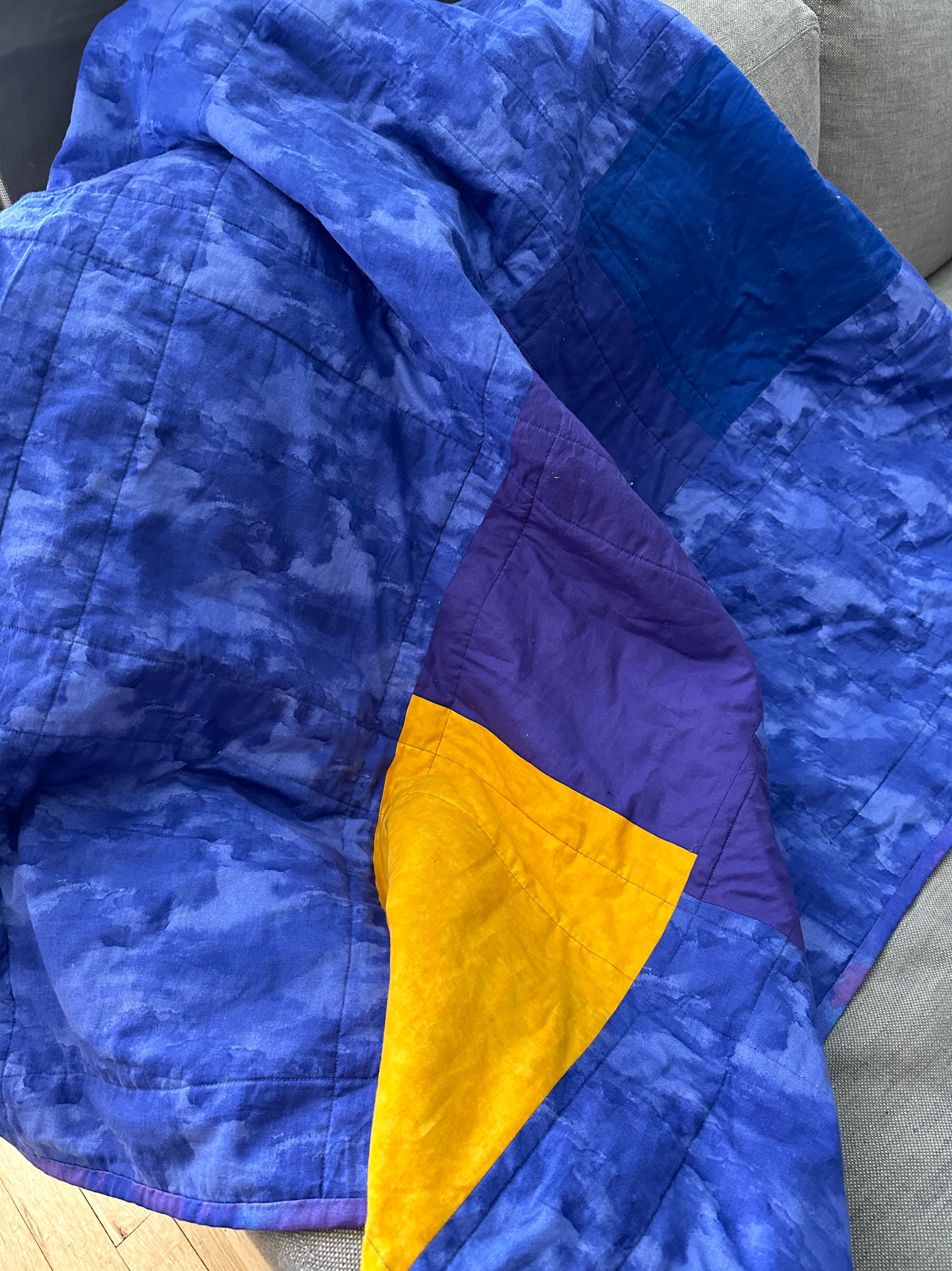 the back side of a blue and purple quilt with some random pattern and a pop of yellow